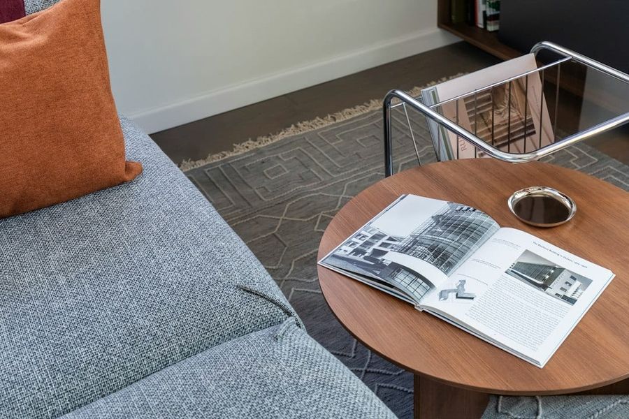 Slim tapered walnut legs under a low mid-century side table showing generous floor clearance in a minimal living room