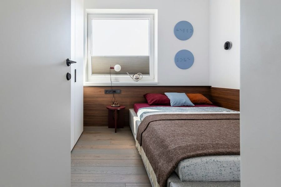 Small bedroom with a neatly made bed, window light and cool blue decor